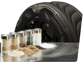 Containers of materials used in sustainable tire manufacturing on a table with Goodyear tire