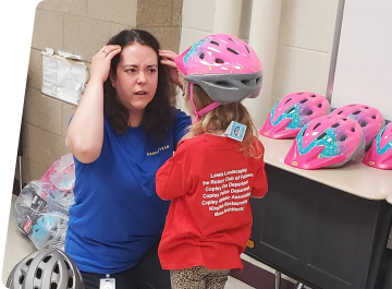 woman helping child with bike helmet