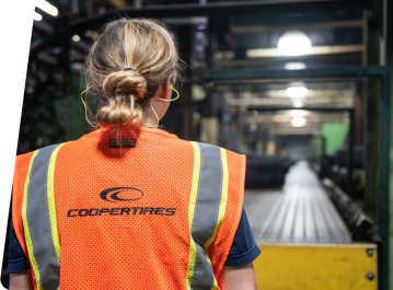 Corporate associate walking in a tire plant wearing an orange vest