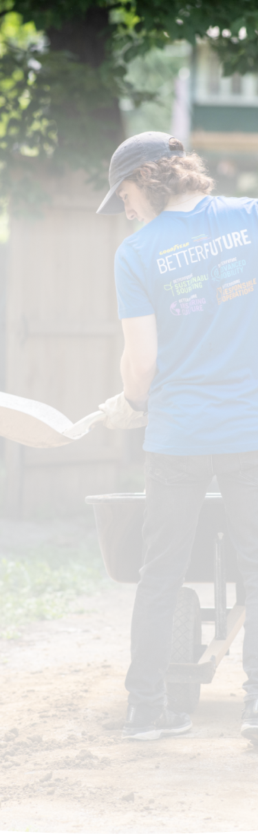 Goodyear corporate associate volunteering holding a shovel and wearing a Goodyear Global Week of Volunteering "Better Future" t-shirt