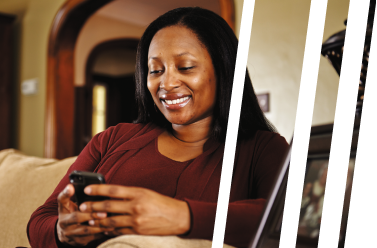 Woman smiling while using her smartphone on a living room couch