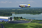 The Goodyear Tire & Rubber Company's newest blimp, Wingfoot One, flies over some of the more than 2,000 people who attended its christening on August 23, 2014.