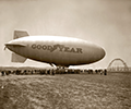 With the shell of the Goodyear Airdock rising in the background, the Goodyear blimp Mayflower is christened in 1929. The ship was named after the America Cup defenders in international yachting, as were the Puritan, Volunteer, Vigilant and Defender. Mayflower became the first Florida-based Goodyear airship.